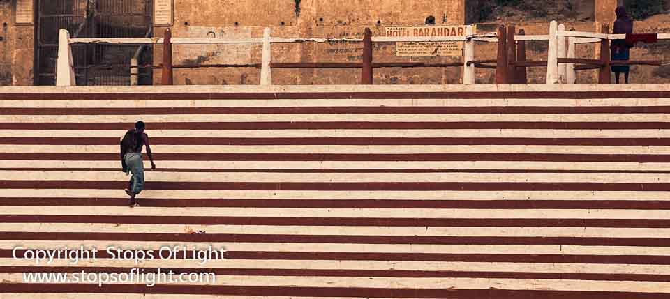 A priest - his early morning dip in the river Ganges over and done with - climbs the steps to a temple - Varanasi, India