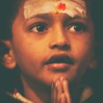 A child folds its hands in reverence, Ganga aarti, Varanasi - India